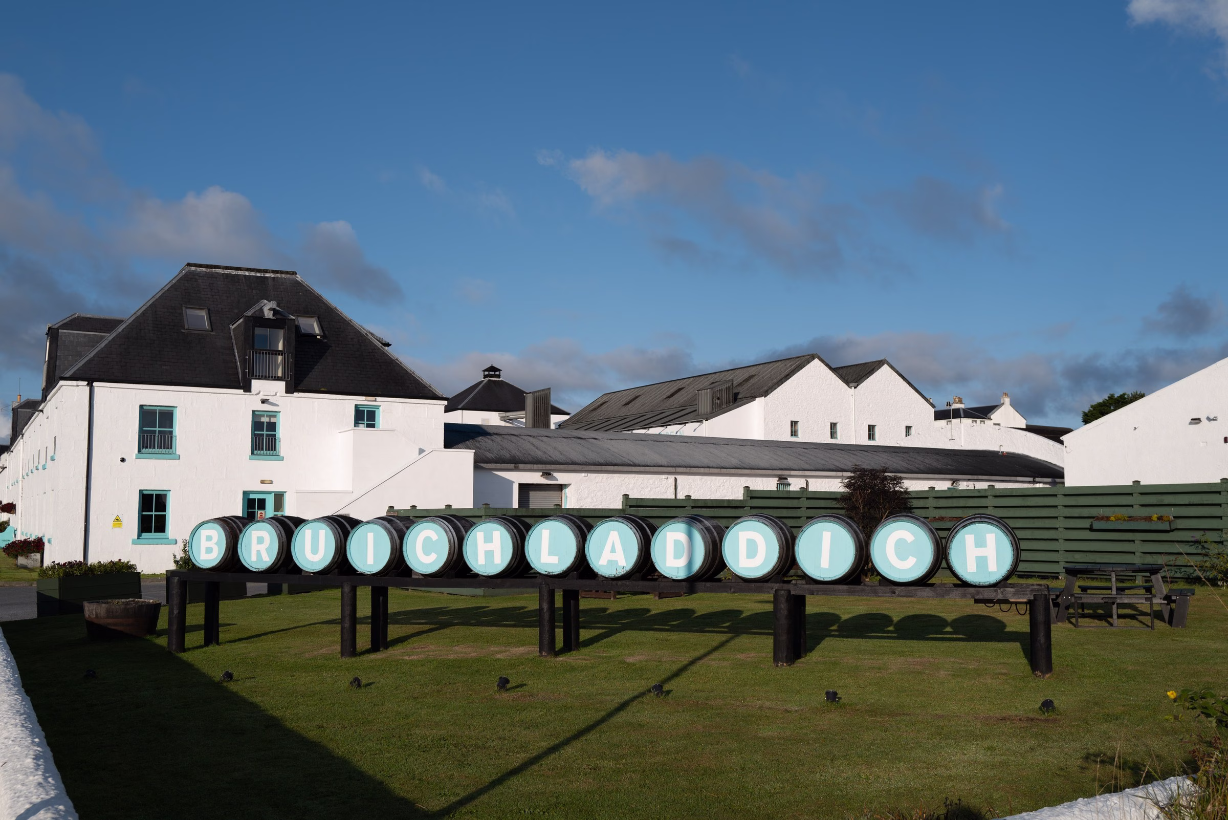 Bruichladdich Distillery whitewashed buildings on Islay with painted barrel-end signage spelling out the brand name