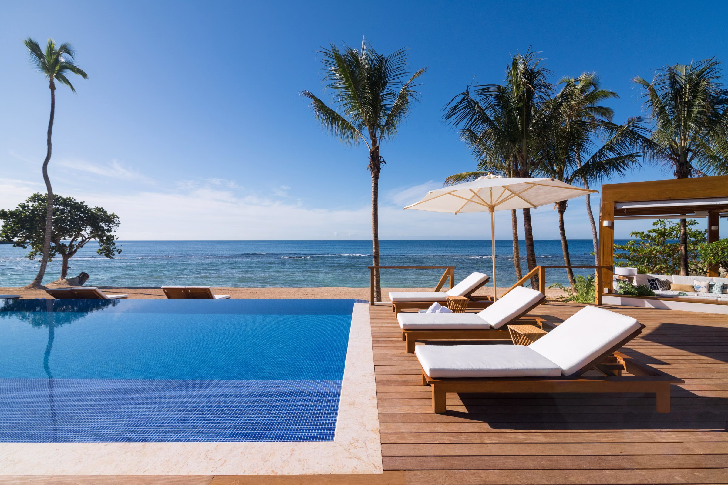 Casa de Campo Minitas Beach Club infinity pool and teak deck with white loungers and palms overlooking the Caribbean Sea