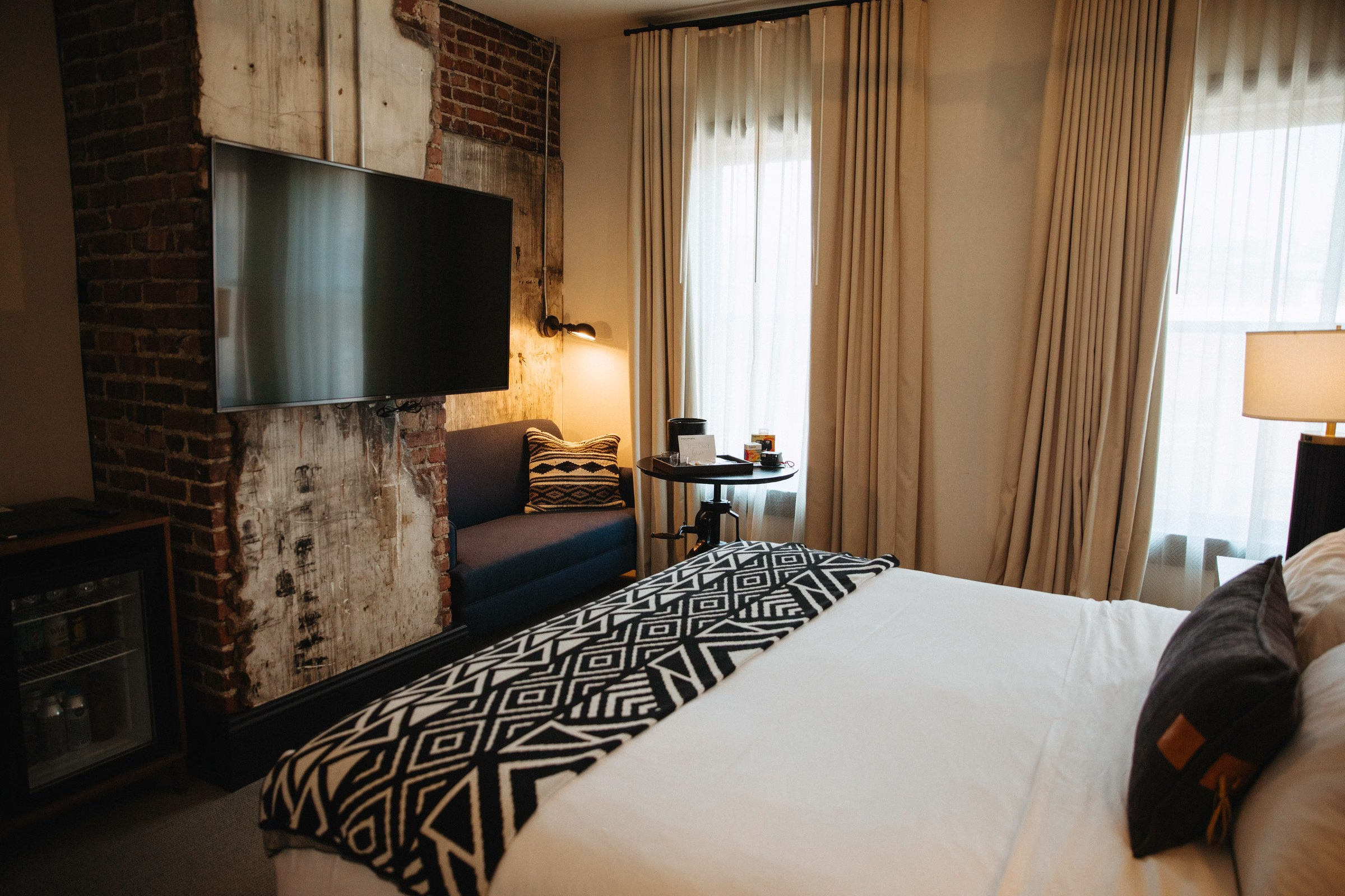 Crossroads Hotel Kansas City guest room with exposed brick wall and warm wood accents