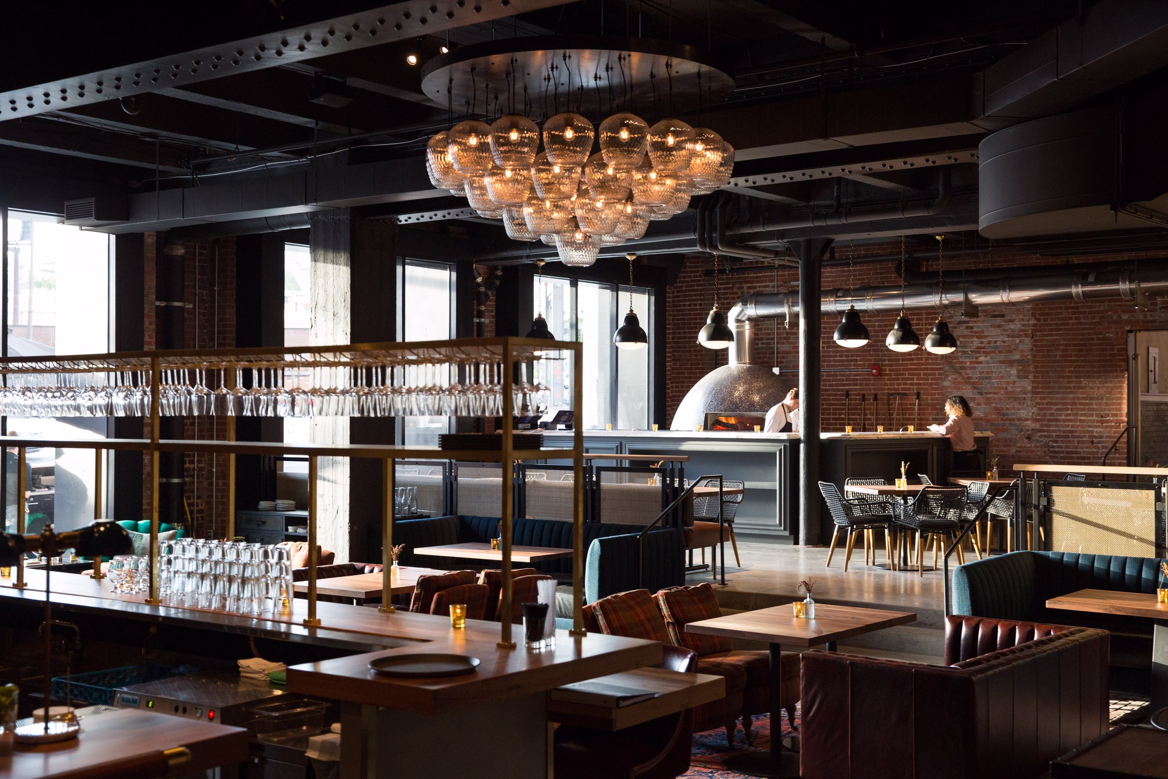 Crossroads Hotel XR restaurant lobby with glass-bulb chandelier and woodfire pizza oven in Kansas City