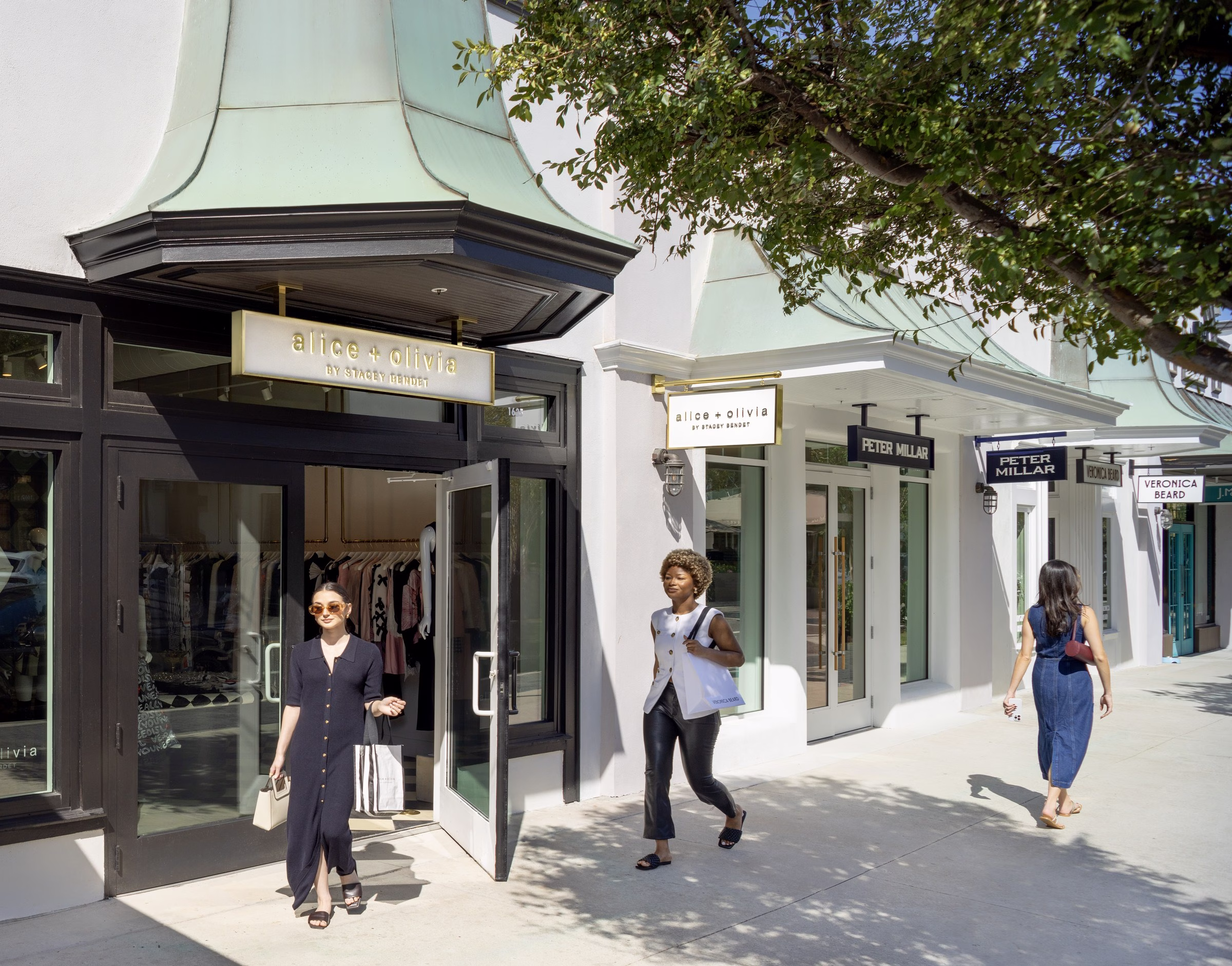Hyde Park Village Tampa Alice + Olivia boutique storefront with shopper exiting onto the village walkway