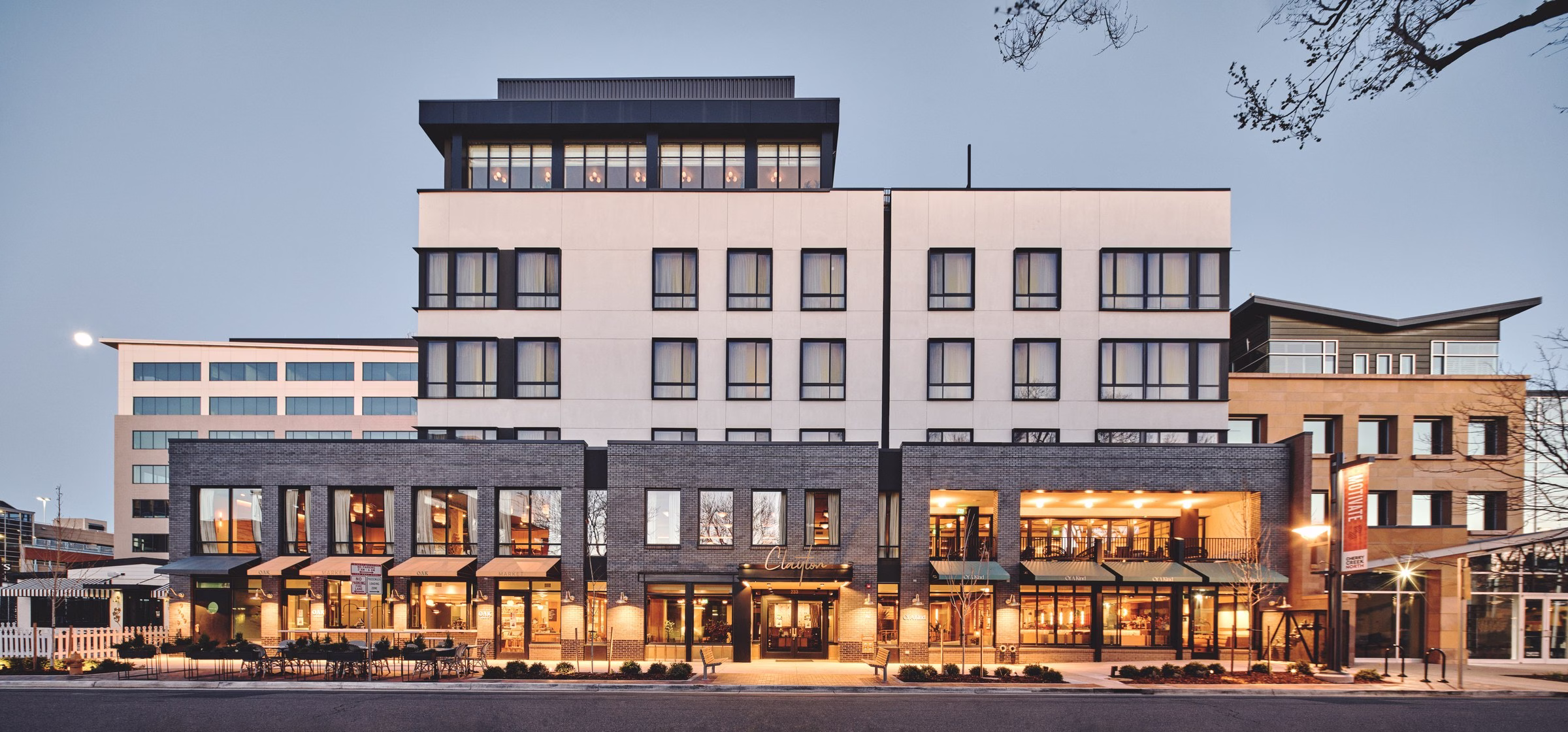 Makeready Clayton Hotel exterior at dusk with warm-glowing facade and string lights