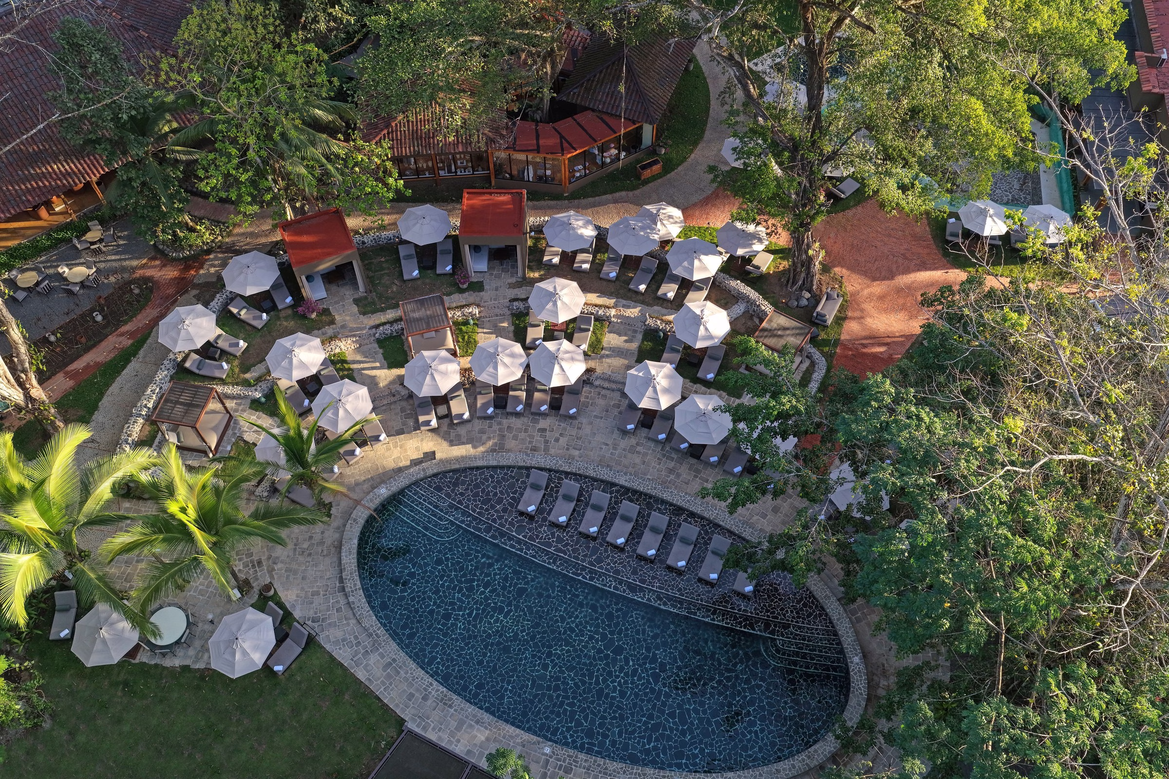 Santa Lucia Jungle Hacienda Costa Rica aerial view of the curved pool, courtyard cabanas, and surrounding rainforest