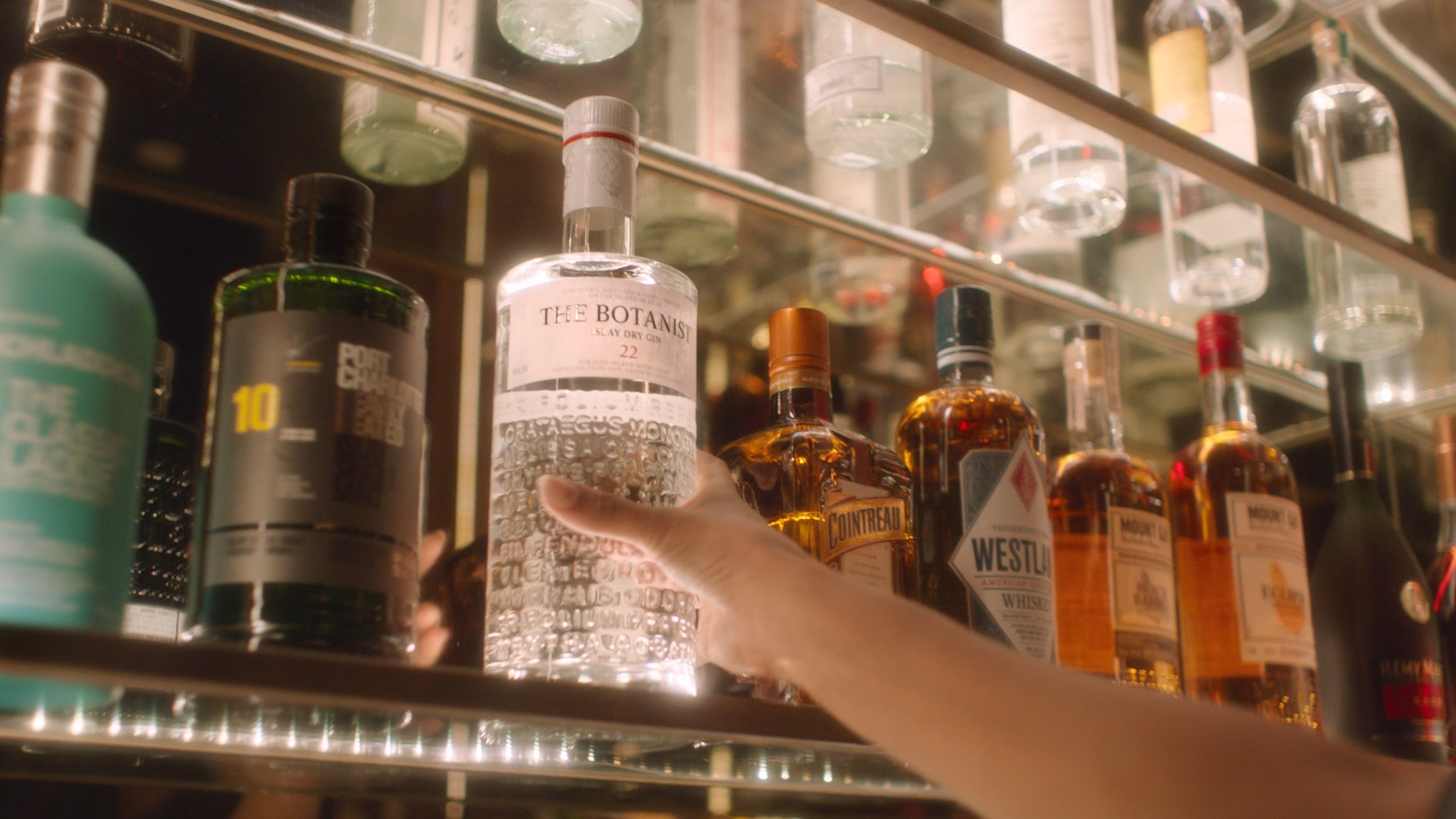 The Botanist Islay Gin lineup on a bar shelf among other premium spirits