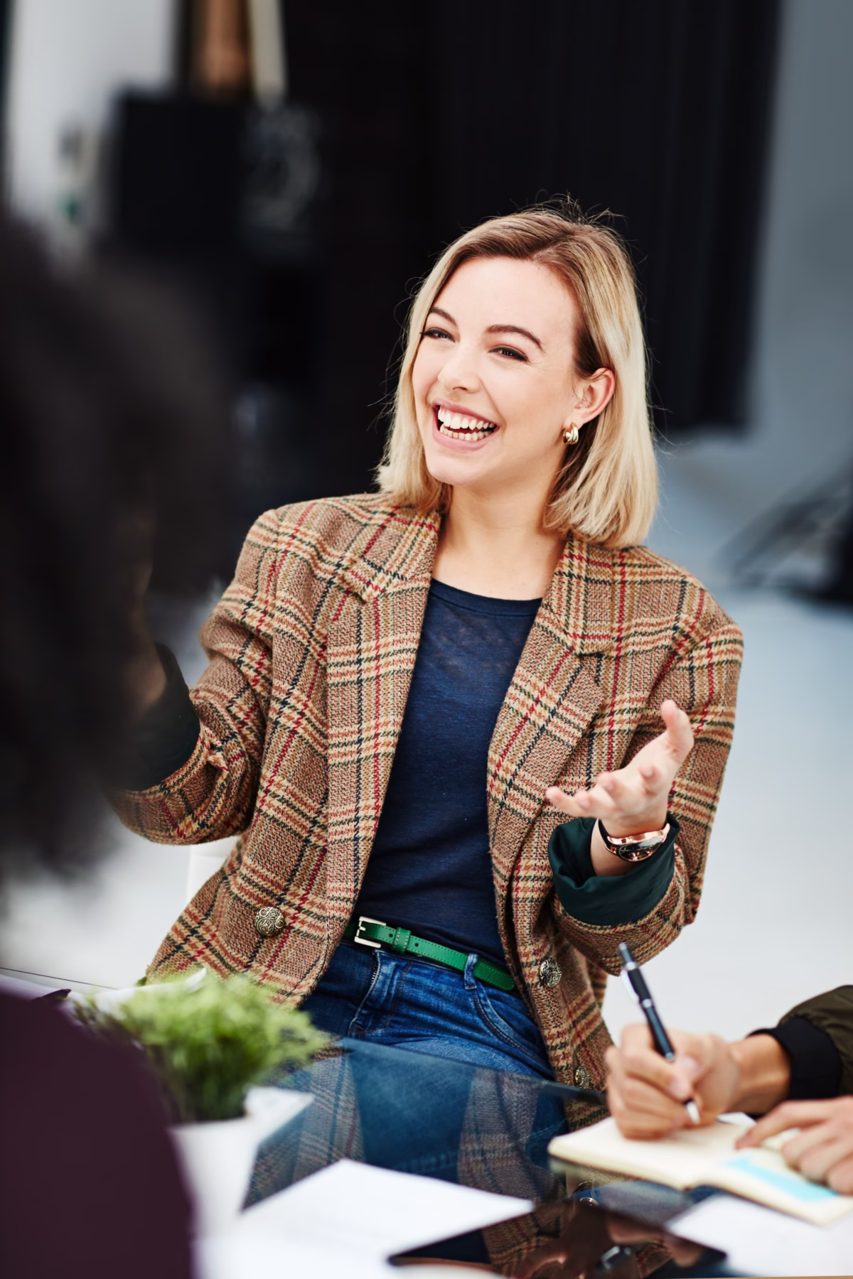 Professional businesswoman in plaid blazer laughing during corporate meeting discussion at modern office